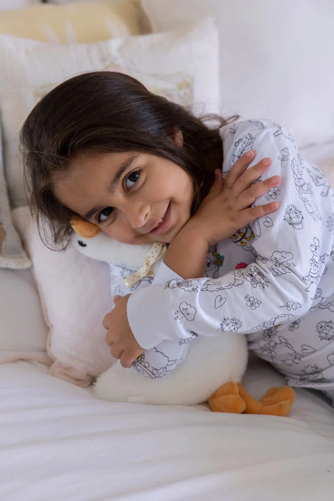 A smiling girl embraces her plush Henry the Goose toy while wearing Henry the Goose pajamas with creative designs.