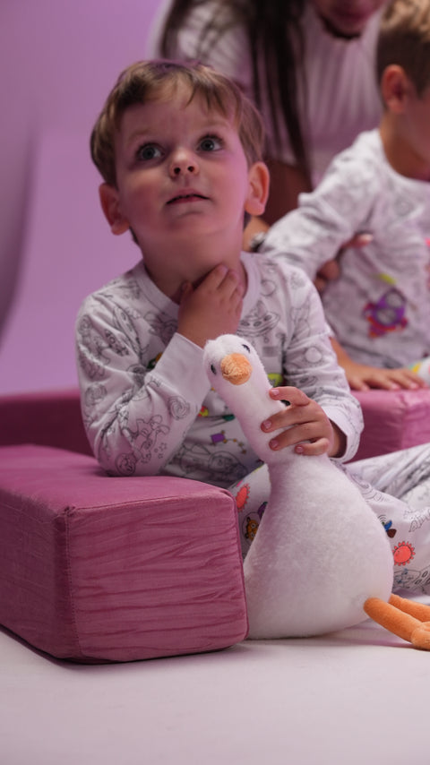 A child in pajamas holding a plush goose toy.