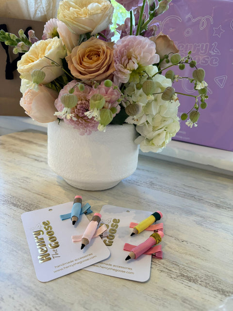 Colorful pencil-shaped hair clips arranged on "Henry The Goose" branded cards. 