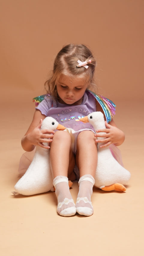 A child holding two plush goose toys. 