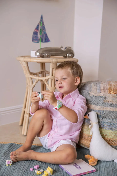 Kid playing with digital watch and markers.